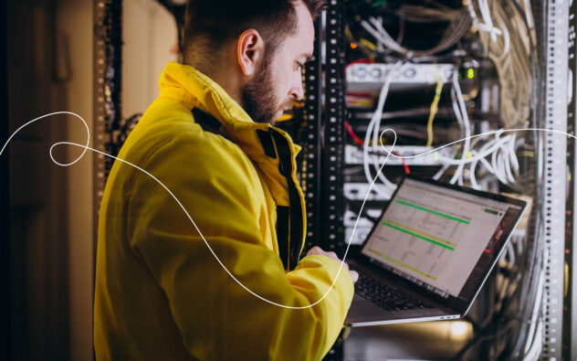 Un homme travaille sur son ordinateur portable dans une salle avec des serveurs informatiques